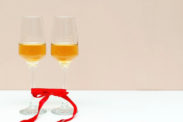 Due bicchieri di champagne con nastro rosso su sfondo tavolo bianco con copia spazio san valentino amato