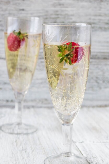 Due bicchieri di champagne e fragole su sfondo bianco