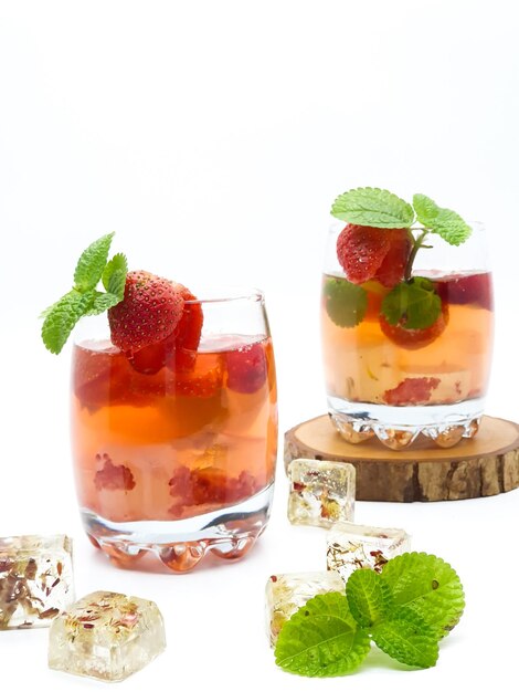 Due bicchieri di cocktail alla fragola con menta su un blocco di legno.