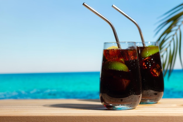Due bicchieri di cocktail Cuba Libre sulla spiaggia tropicale estiva