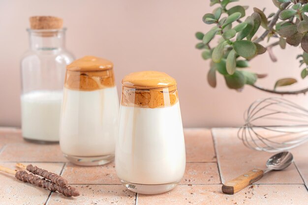 Due bicchieri di dalgona a base di caffè istantaneo montato zucchero e latte serviti in tavola con pianta