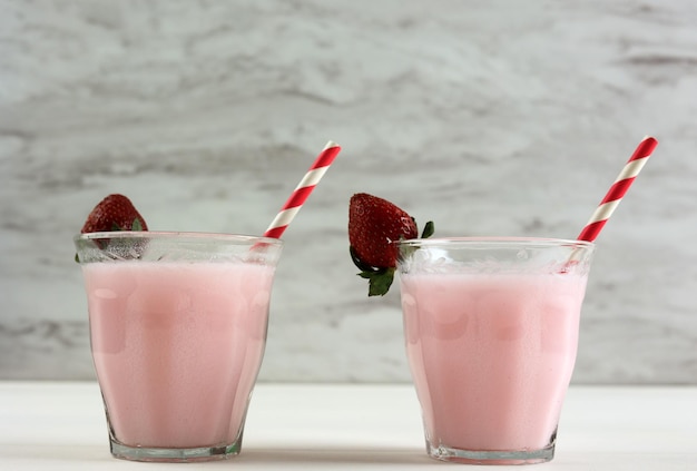 Due bicchieri di latte alla fragola sul tavolo bianco