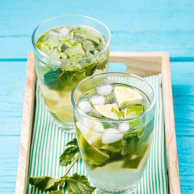 Due bicchieri di mojito in scatola di legno con la menta