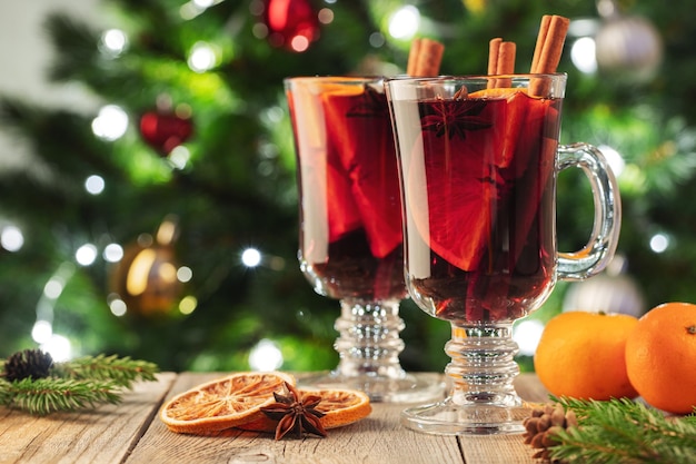 Due bicchieri di Natale vin brulé o gluhwein con spezie e fette di arancia su un tavolo rustico contro...