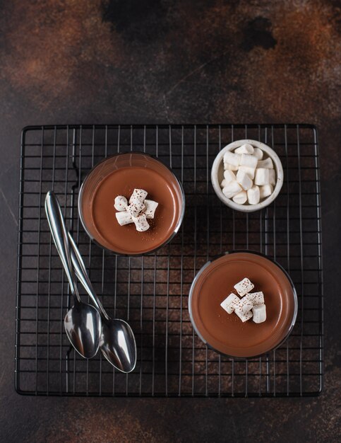 Due bicchieri di panna cotta, decorati con marshmallows superficie martellata marrone,