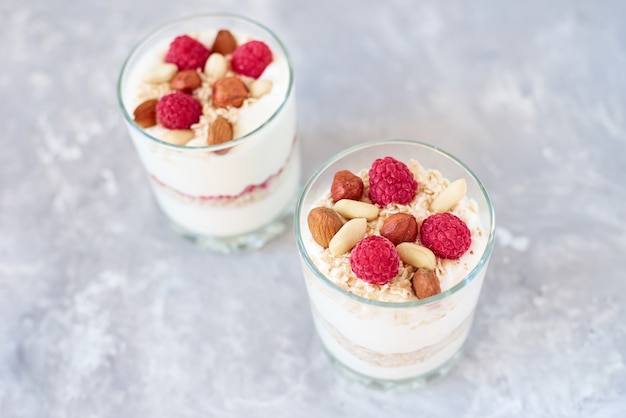 Due bicchieri di una granola di yogurt greco con lamponi, fiocchi d&#39;avena e noci, vista dall&#39;alto. Alimentazione sana