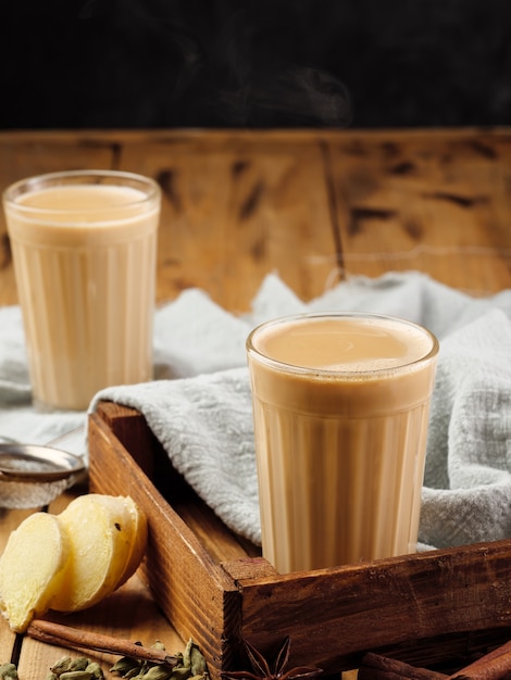 due bicchieri di vetro sfaccettati su un tavolo di legno con la tradizionale bevanda indiana masala chai.