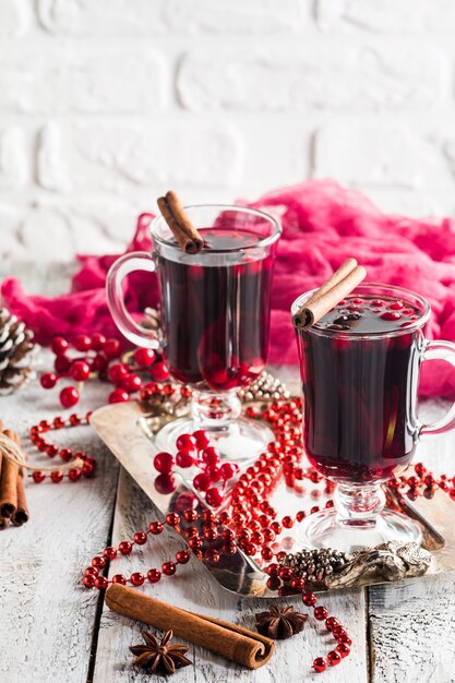 Due bicchieri di vin brulè caldo con spezie su bianco