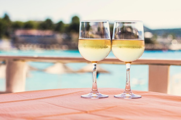 Due bicchieri di vino bianco contro la vista sul mare nel bar sulla spiaggia. Ristorante sulla spiaggia
