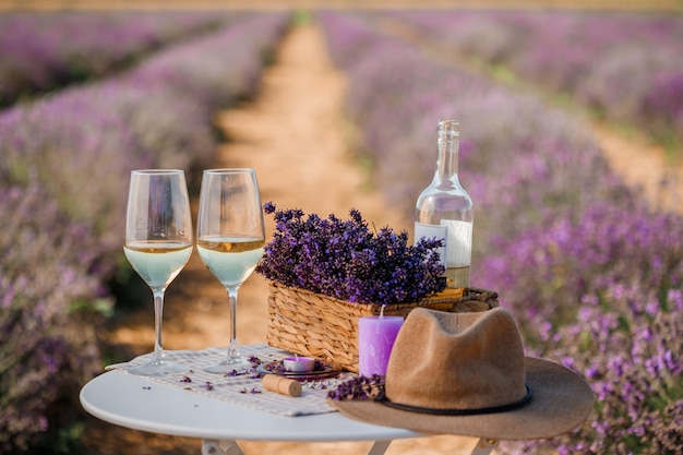 Due bicchieri di vino bianco e una bottiglia in un campo di lavanda a Provance Fiori viola sullo sfondo