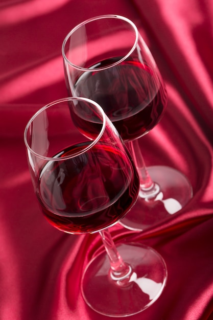 Due bicchieri di vino con vino rosso sulla seta rossa