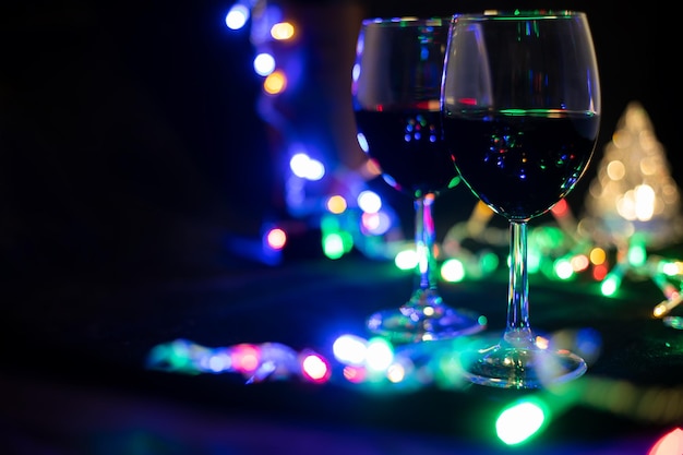 Due bicchieri di vino in una ghirlanda splendente con un albero di natale giocattolo