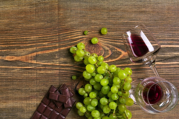 Due bicchieri di vino rosso, uva verde e cioccolato, vista dall'alto. Copia spazio. Natura morta. Lay piatto