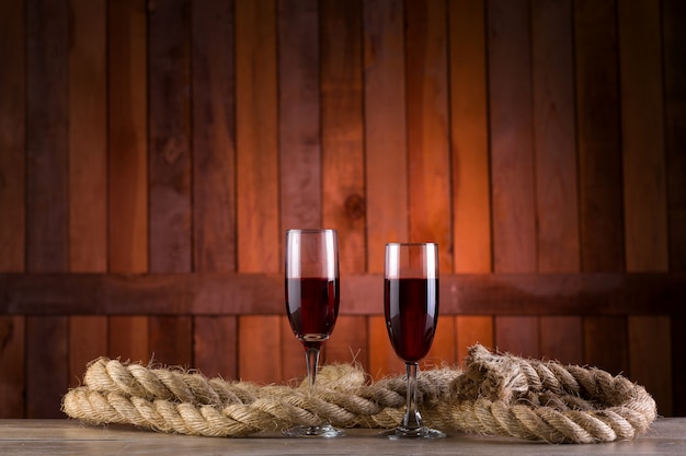 due bicchieri di vino su fondo in legno con una corda