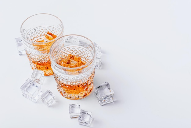 Due bicchieri di whisky con ghiaccio su uno sfondo bianco con posto per il testo