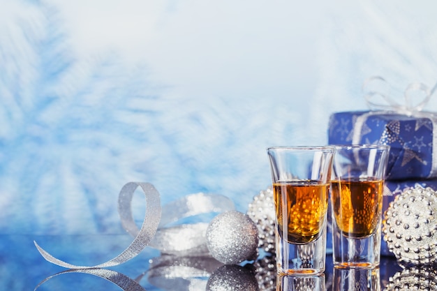 Due bicchieri di whisky o bourbon con decorazioni natalizie su un leggero bokeh