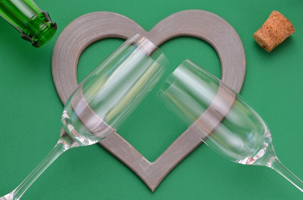 Due bicchieri e una cornice a forma di cuore su sfondo verde