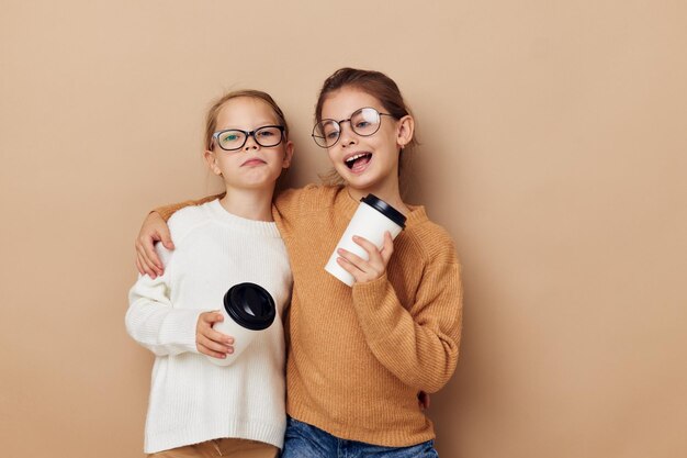 Due bicchieri usa e getta per bambine in posa su sfondo beige