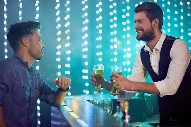 Due birre pronte per l'uso Inquadratura ritagliata di un barista che serve drink a un uomo in una discoteca