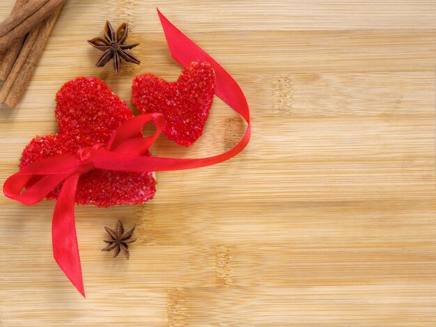 Due biscotti a cuore rosso fatti a mano con un fiocco rosso alla cannella