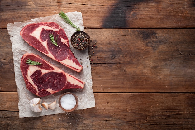 Due bistecca di ribeye di marmo grezzo fresco con spezie.