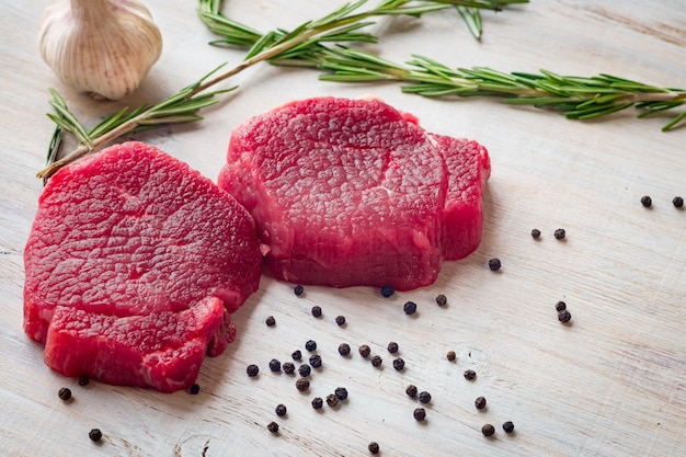 due bistecca mignion file di manzo crudo con aglio e pepe sul tavolo di legno bianco