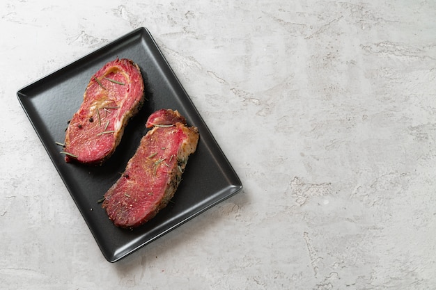 Due bistecche di carne cruda fresca sul piatto in ceramica nera