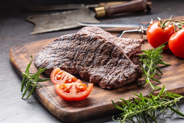 Due bistecche di fesa di manzo con erbe pomodori sale e spezie sul bordo del macellaio.