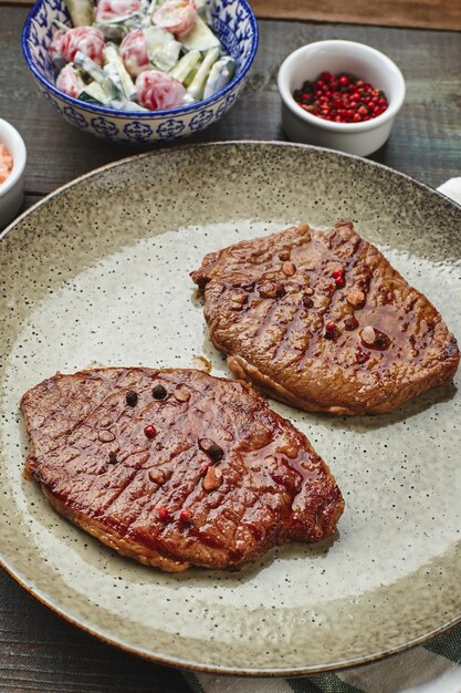 Due bistecche di ribeye alla griglia spezie e insalata di cetrioli con panna acida