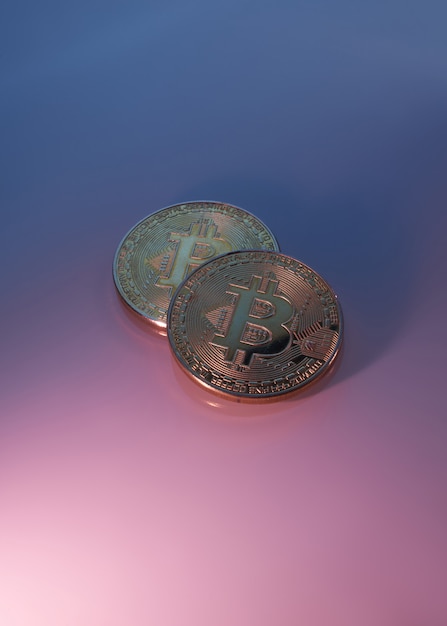 Due bitcoin dorati isolati sul primo piano porpora rosa del fondo con lo spazio della copia