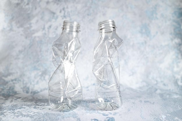 Due bottiglie di plastica vuote schiacciate preparate per il riciclaggio di tappi di plastica ed etichette rimosse