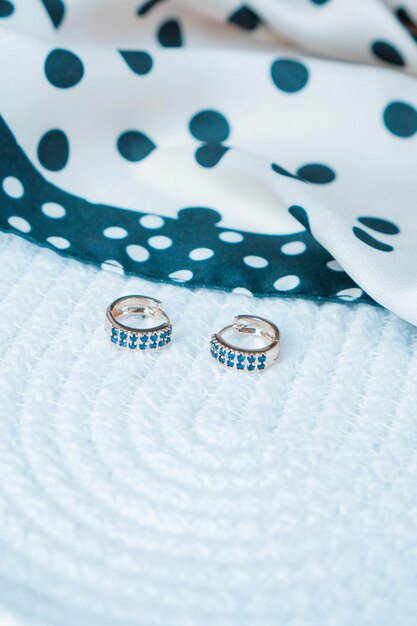 due bottoni d'argento con sopra diamanti blu e bianchi.