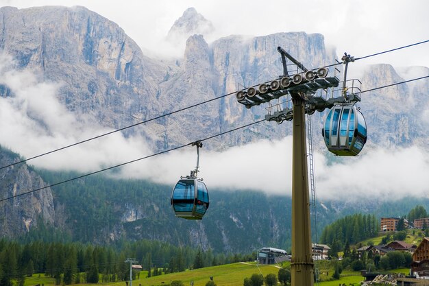 Due cabine della funivia contro le Dolomiti coperte di nuvole