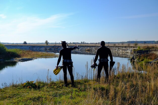 Due cacciatori subacquei sulla riva del fiume si preparano a tuffarsi Pesca subacquea Vista posteriore