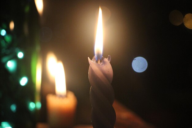 Due candele accese al buio con doppio fuoco e luci bokeh