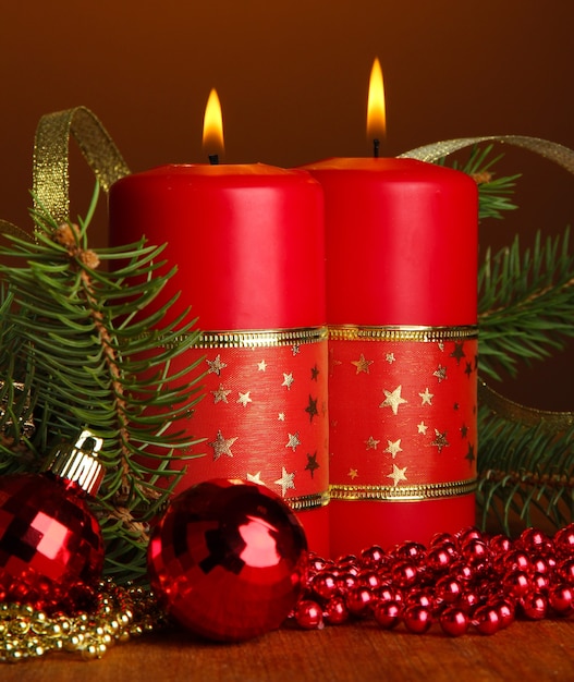 Due candele e decorazioni natalizie, su sfondo marrone