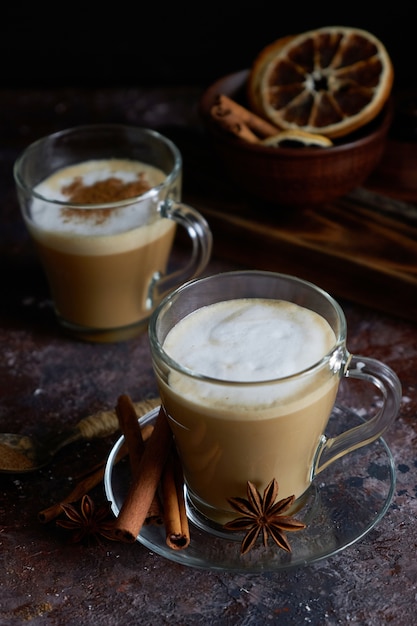 Due cappuccino caldo con schiuma, cannella, zucchero e anice su una superficie marrone