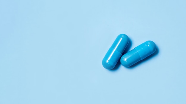 Due capsule blu. Pillole per la salute degli uomini e l'energia sessuale su uno sfondo isolato. Concetto di erezione, potenza. Trattamento di infertilità e impotenza maschili.