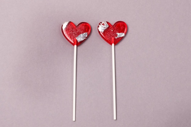 Due caramelle a forma di cuore Lollipop su sfondo di carta grigia Concetto di amore Vista dall'alto Stile minimalista