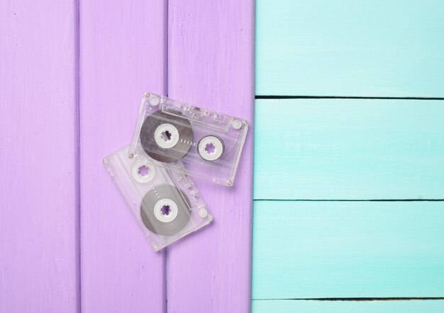 Due cassette audio retrò degli anni '80 su un fondo di legno viola blu. Vista dall'alto.