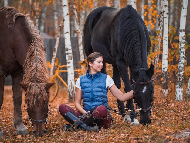 Due cavalieri si siedono sull'erba accanto ai cavalli.