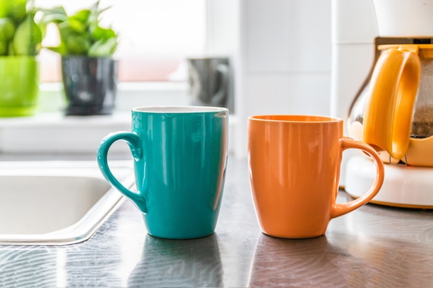 Due cerchi con una bevanda calda stanno sul tavolo. Sullo sfondo c'è una macchina da caffè e un vaso di piante verdi.