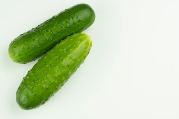 Due cetrioli sono abbondanti su uno sfondo bianco con un posto per la scritta Closeup