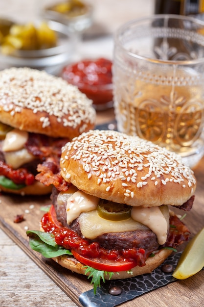 Due cheeseburger su panini al sesamo con jalapeno su una tavola di legno rustica