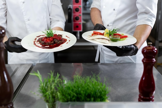 Due chef in una cucina professionale tengono in mano piatti pronti