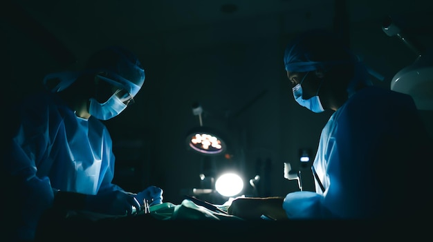 Due chirurghi in una stanza buia con una lampada dietro di loro