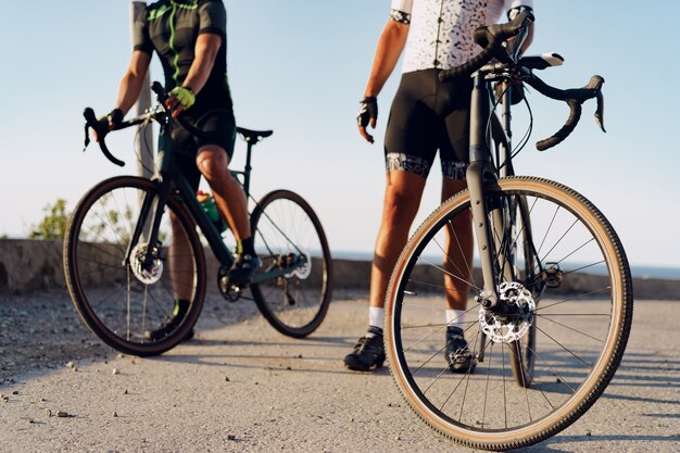 Due ciclisti maschi stanno sulla strada costiera e si riposano