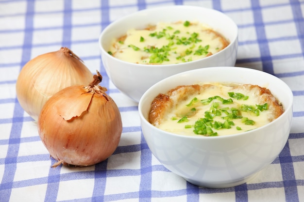 due ciotole bianche piene di deliziosa zuppa di cipolle francese al forno con pane tostato e formaggio