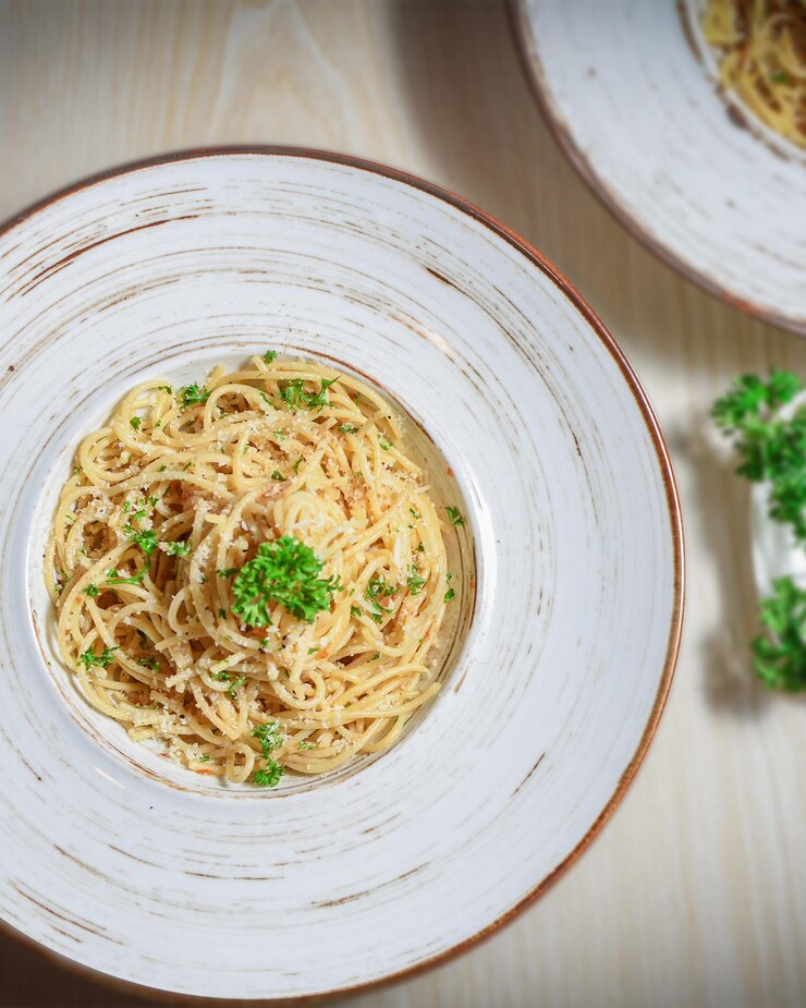 Foto due ciotole di pasta con un contorno verde sul lato.