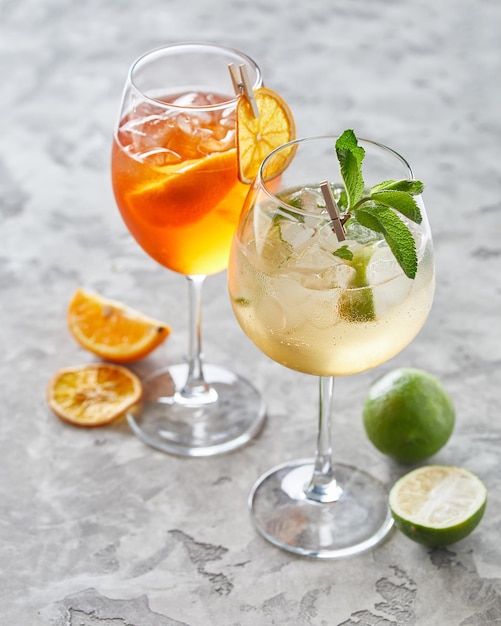 Due cocktail con lime e ghiaccio su sfondo grigio